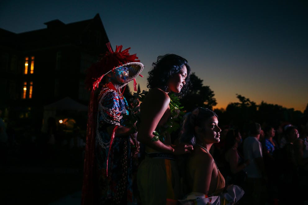 A faint orange glow lights the evening sky as three figures stand together in a sliver of light