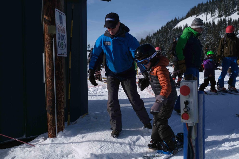 Ski area manager helping snowboarder on tube lift