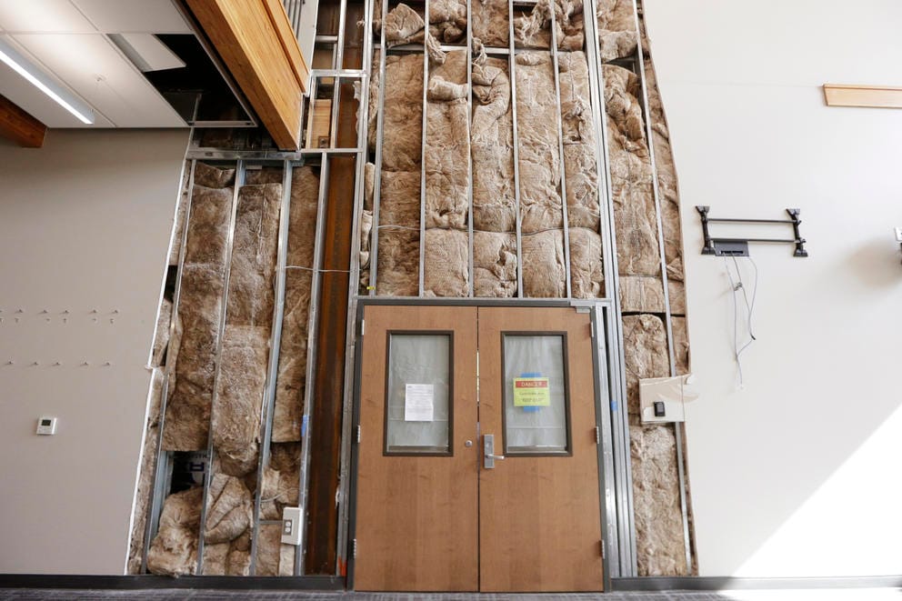 Double doors with the drywall ripped away, exposing the insulation and industrial bars. 