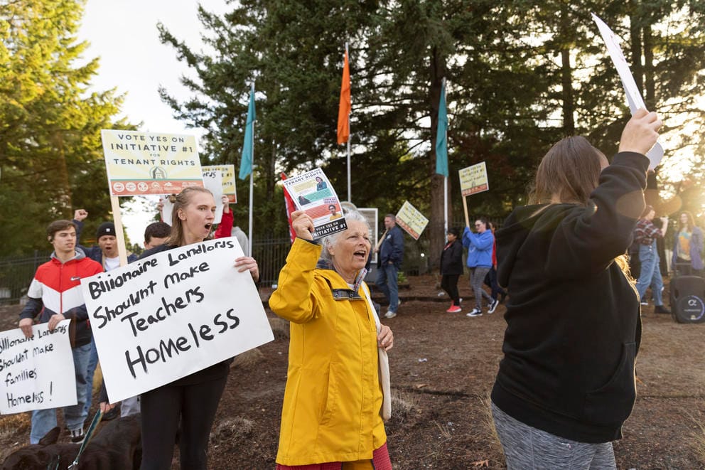 Demonstrators hold signs in support of Initiative 1 