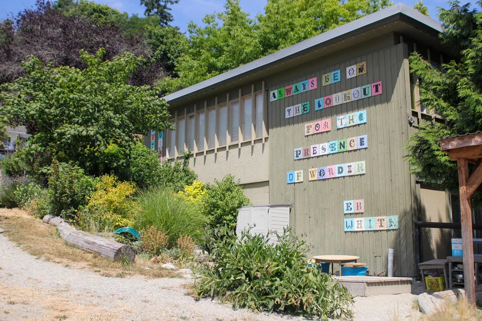 A building on a hillside has a mural with the words, 