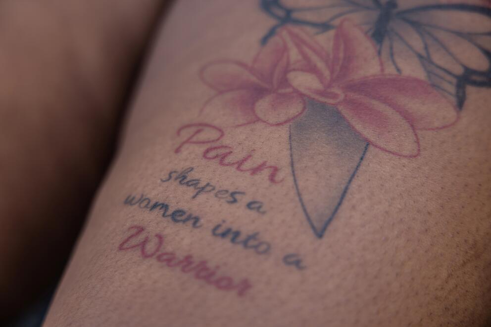 A tattoo on a leg shows a flower and an inscription: 