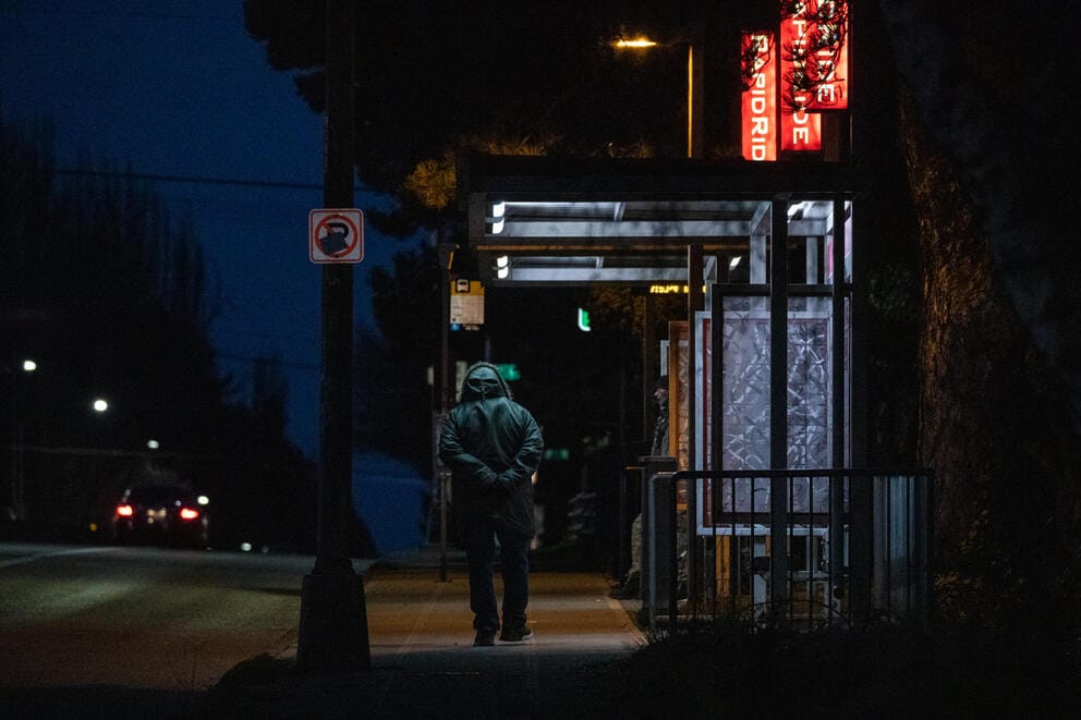 person walking past a bus stop on Aurora Avenue North