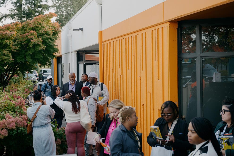 A group of people stands out side a yellow building