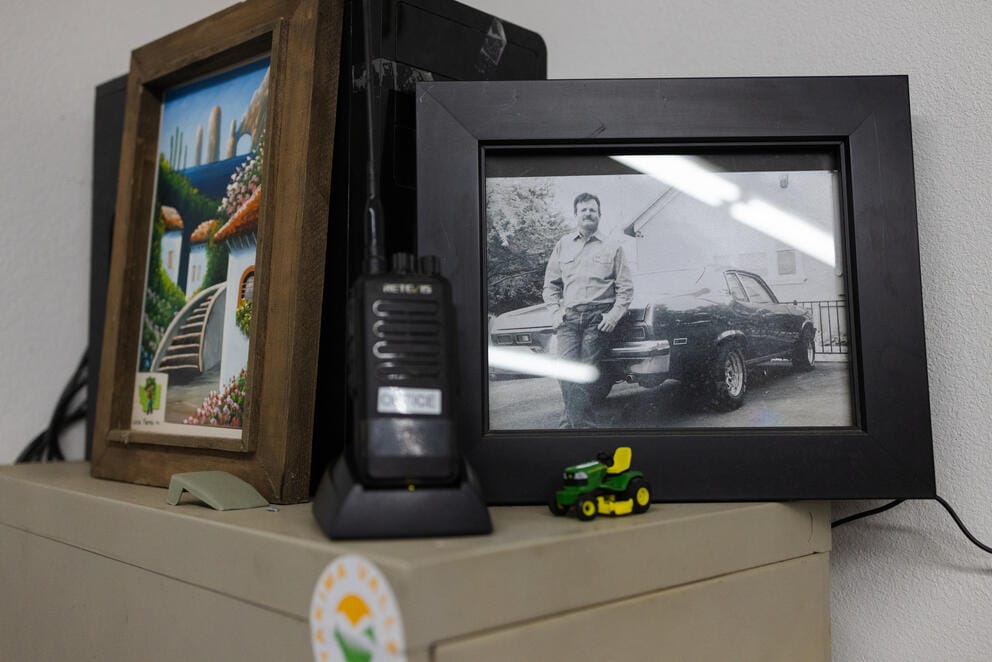 A close up of a framed black and white photograph of a man leaning against a car