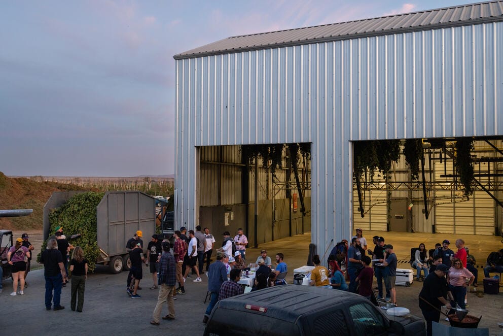 A group is gathered for a dinner event at dusk outside the hops processing facility