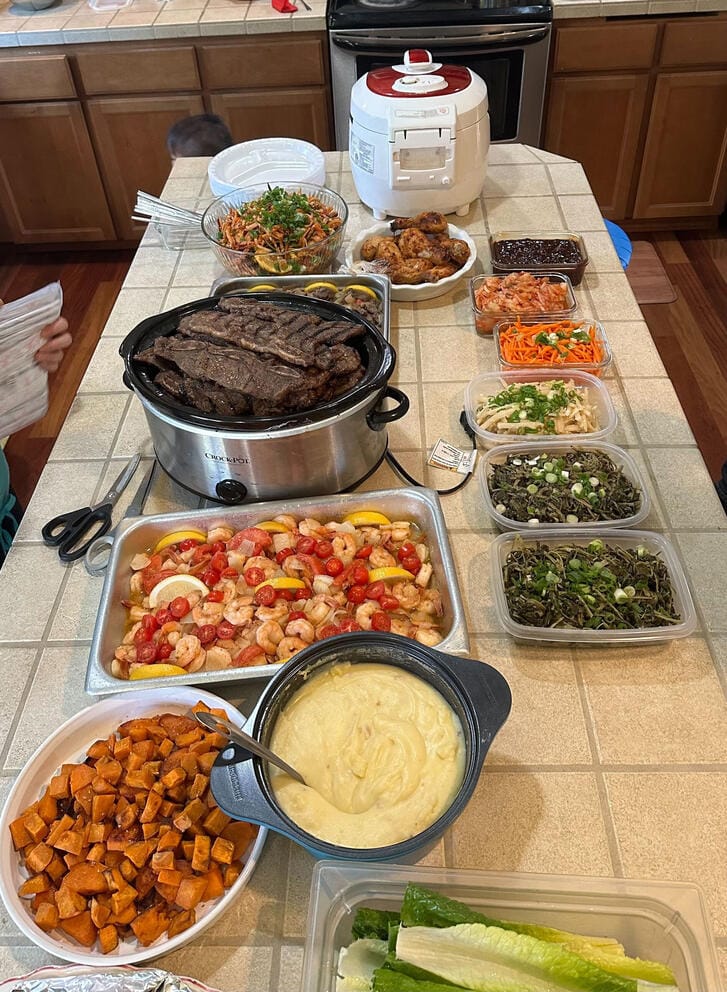 Jane Hong, a Korean-American born and raised in Federal Way, shows her family’s 2023 Thanksgiving spread which included Korean-style beef short ribs called galbi (center in slow cooker), kimchi and other Korean side dishes, and also American dishes like fried chicken, mashed potatoes, and roasted sweet potatoes. (Photo courtesy of Jane Hong)