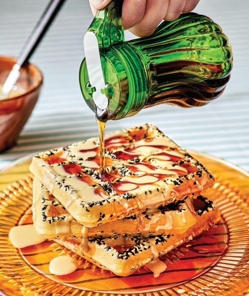 syrup being poured onto a stack of waffles