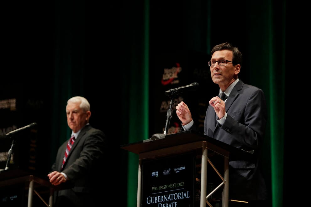 On the left, Dave Reichert stands behind a podium next to Bob Ferguson, left, at a Washington Debate Coalition debate