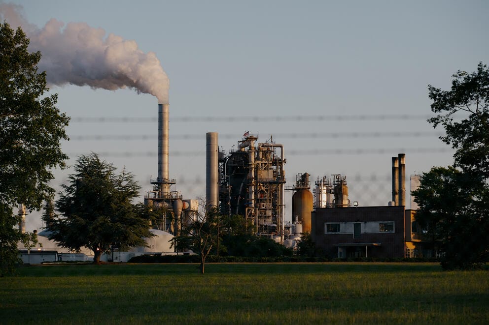 Smoke comes out of a chimney at an oil refinery