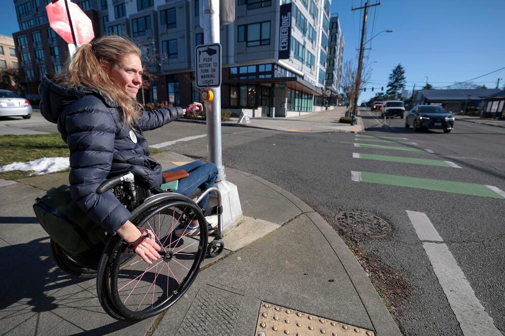 a woman in a wheelchair waits to cross the street in seattle