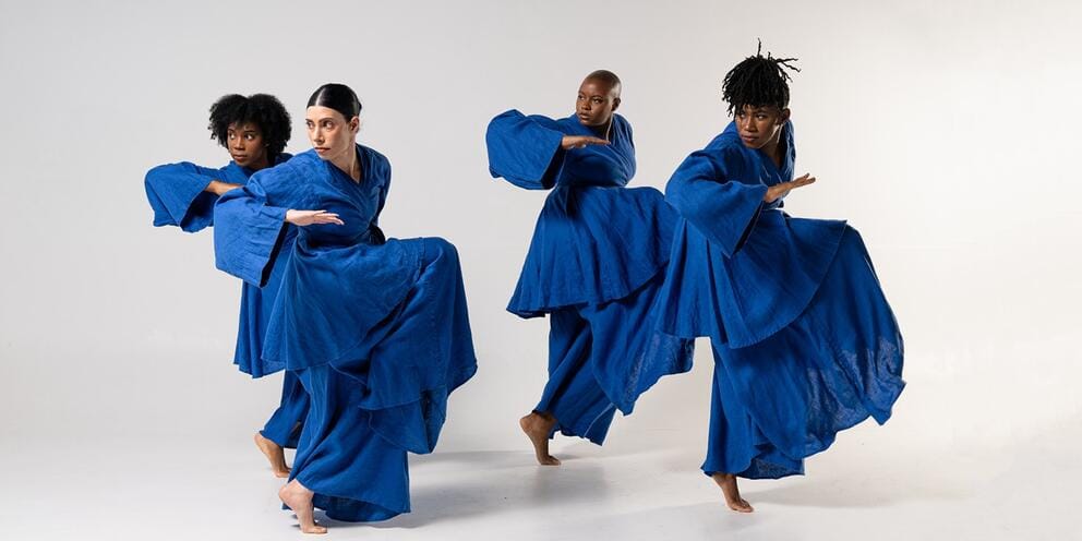 photo of four dancers performing in formation in bright blue dresses
