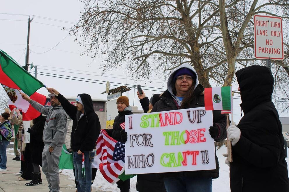 A person holds a sign that says, 