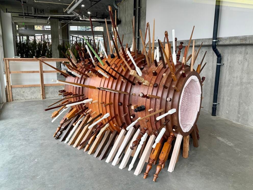 a large cyclindrical wooden sculpture with spikes sticking out all over and a visibly soft interior